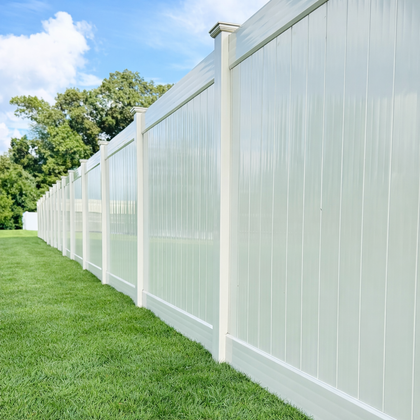 White vinyl fence bordering green lawn under a blue sky.