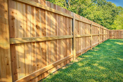 Wooden privacy fence in a grassy yard, with trees in the background.