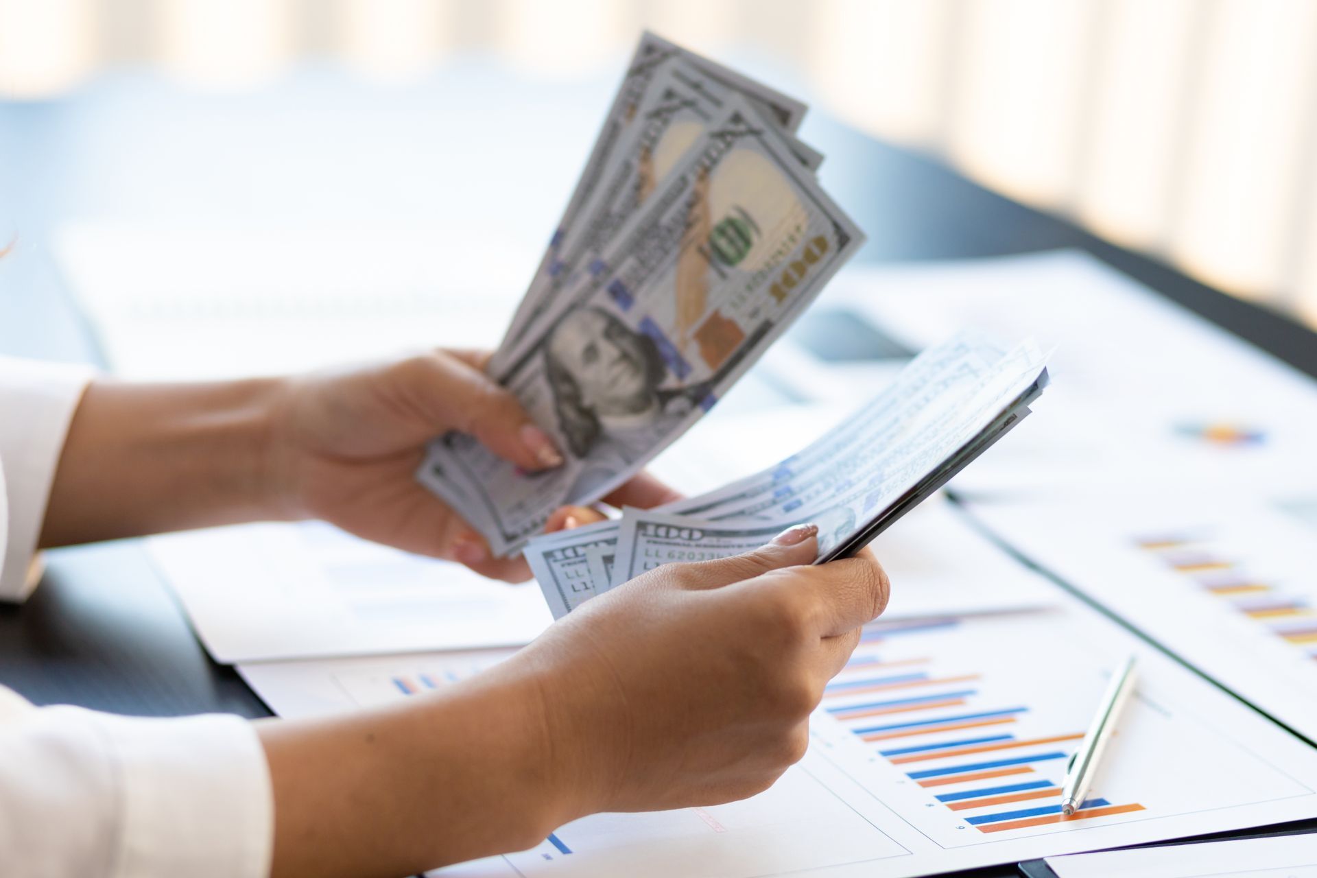 A person is holding a bunch of money and a tablet.