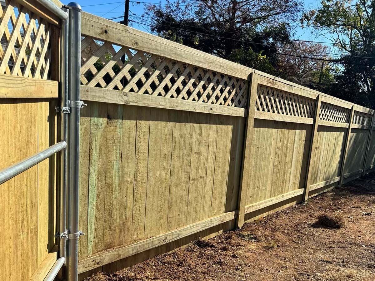A wooden fence with a lattice design and a metal gate.