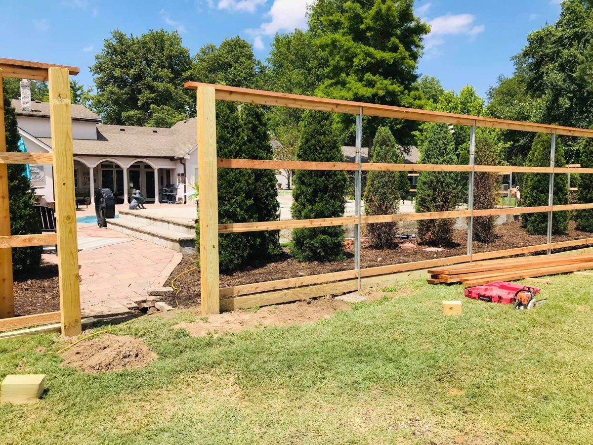 A wooden fence is being built in the backyard of a house.