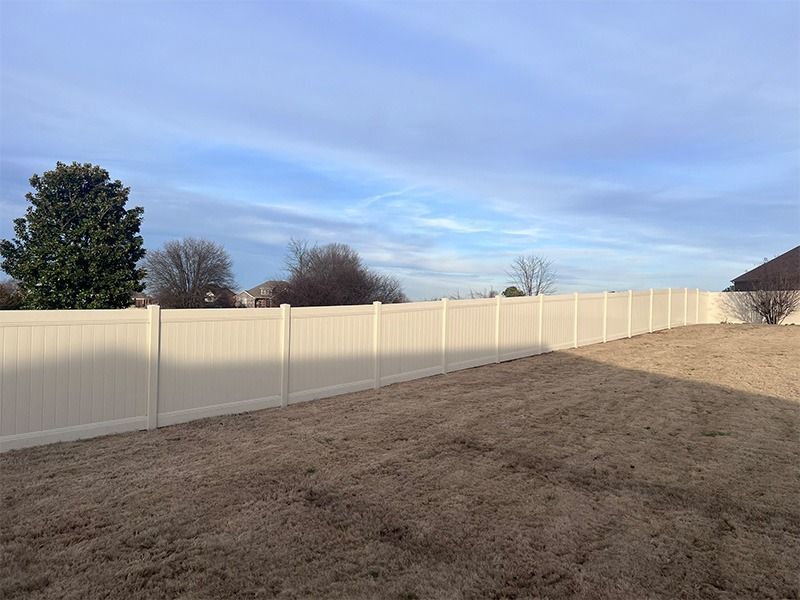 There is a white fence in the backyard of a house.