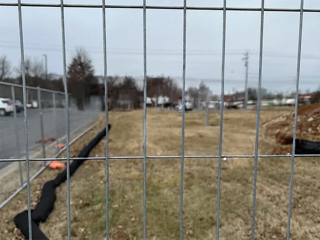 A metal fence surrounds a grassy field.