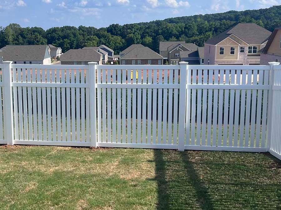 A white picket fence surrounds a lush green yard.