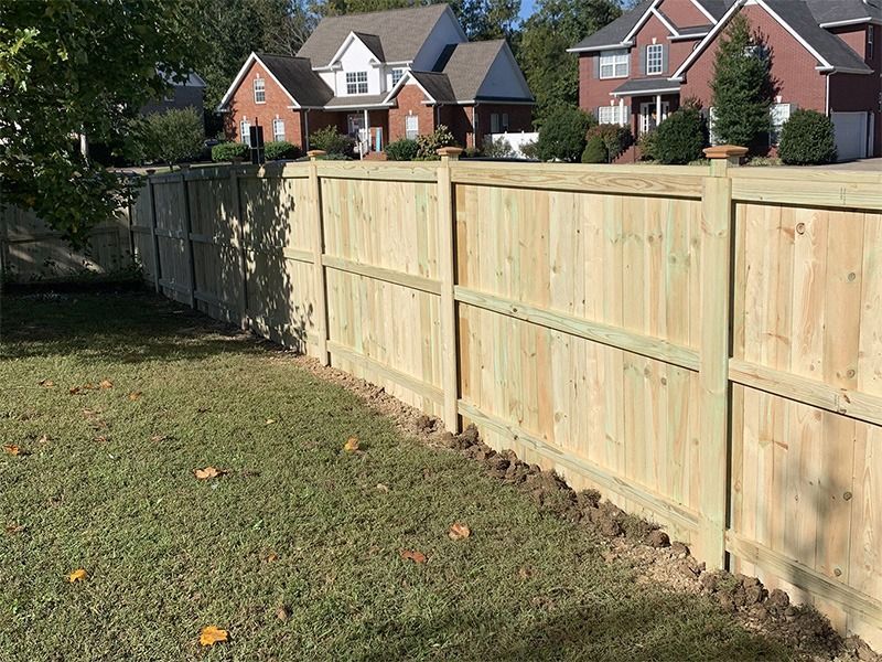 A wooden fence is in the backyard of a house.
