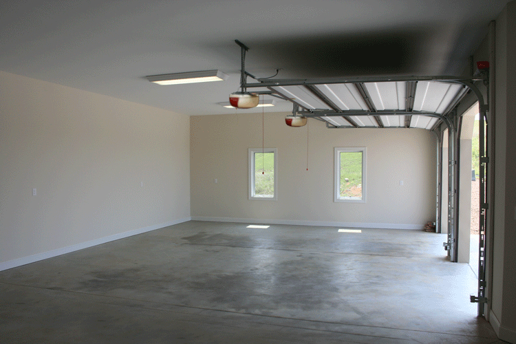 Interior of a large double garage with a white roll up garage door and white walls