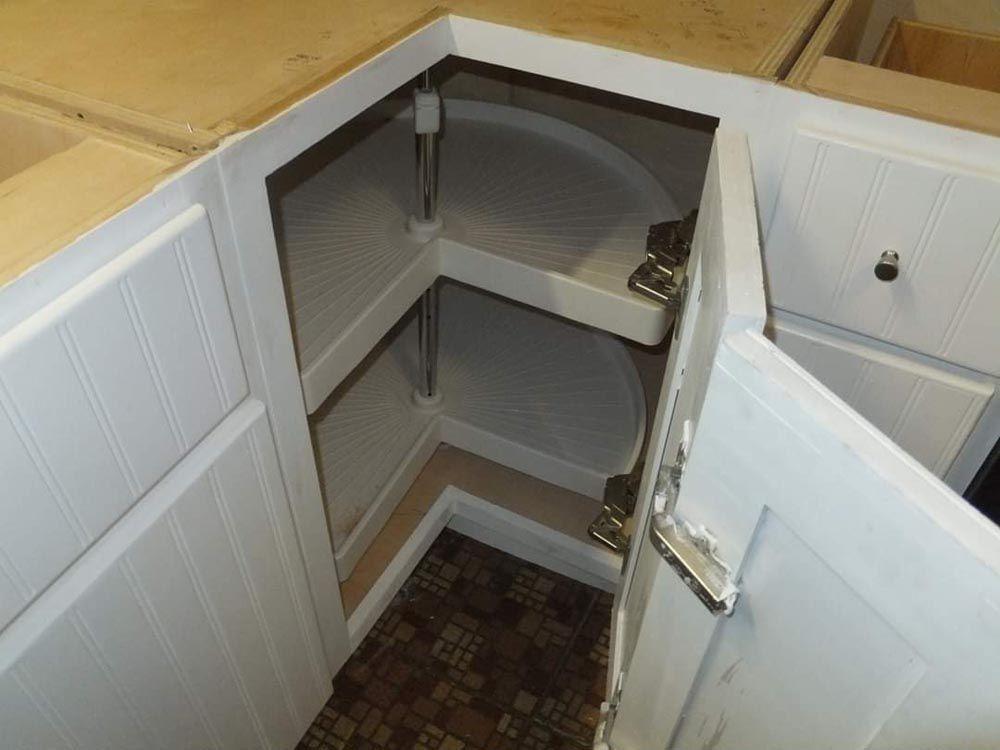 A kitchen cabinet with a corner shelf that is open