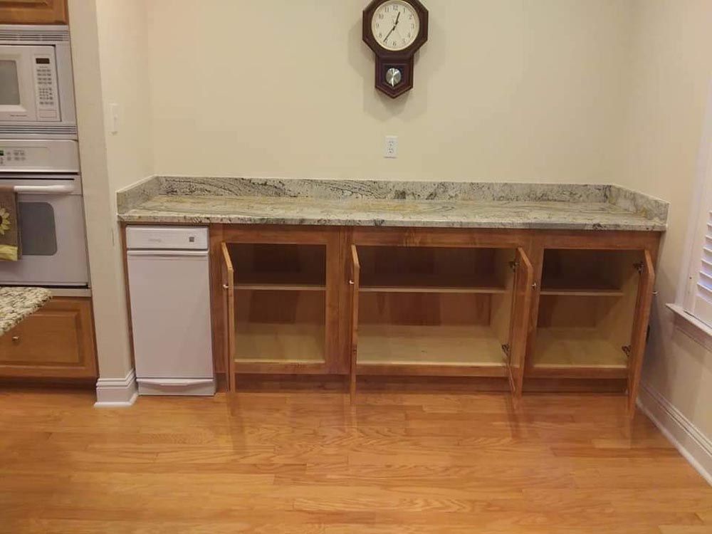There is a clock on the wall above the counter in the kitchen.