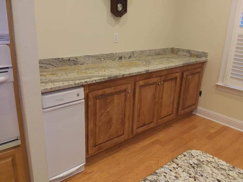 A kitchen with wooden cabinets, granite countertops, and a white dishwasher.