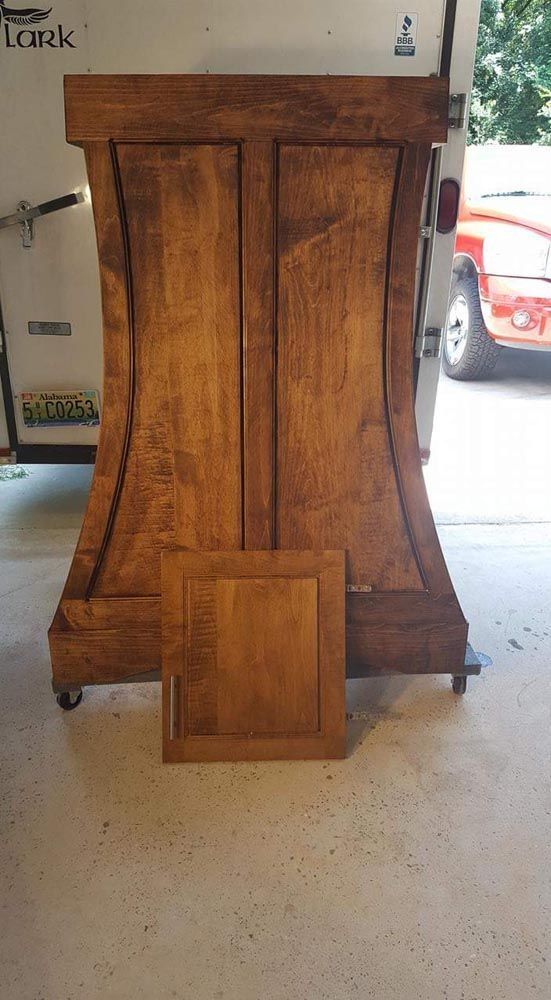 A wooden cabinet is sitting on the floor next to a car.