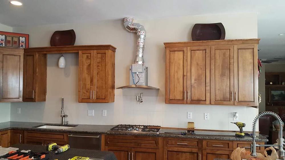 A kitchen with wooden cabinets , granite counter tops , a sink and a stove.