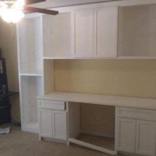A room with a desk, shelves, and a ceiling fan.