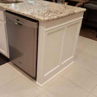 A kitchen island with a stainless steel dishwasher and a granite counter top.