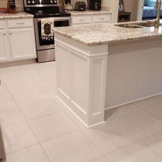 A kitchen with white cabinets, granite countertops, stainless steel appliances, and a large island.