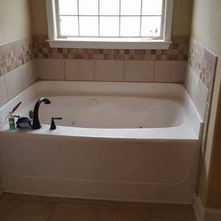 A bathtub in a bathroom next to a window.