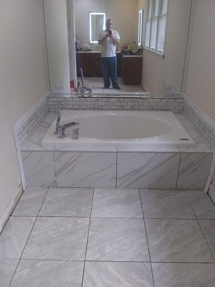 A man is taking a picture of himself in a bathroom with a bathtub.
