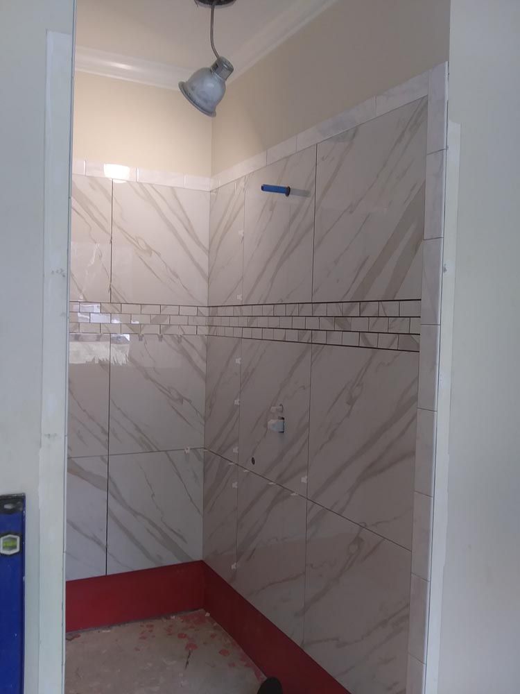 A bathroom with white tiles and a red border is being remodeled.