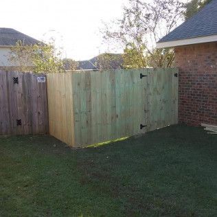A wooden fence with a gate in the backyard of a house.