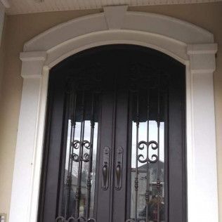 A close up of a wrought iron door with a white frame.