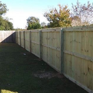 A wooden fence is sitting on top of a lush green field.