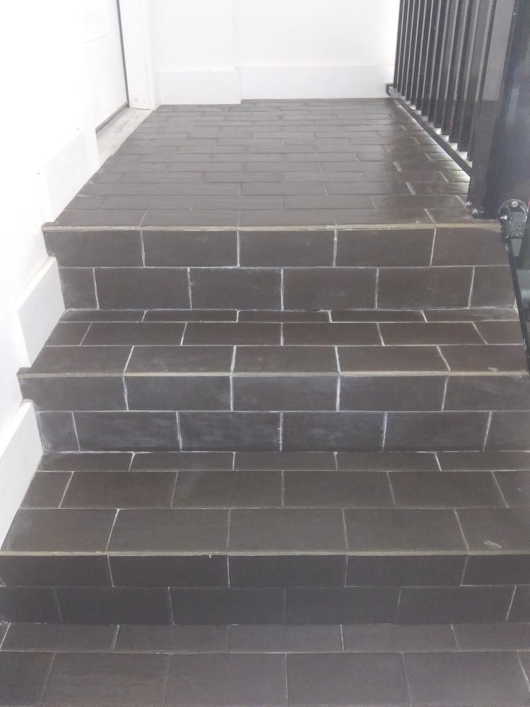 A set of black tiled stairs leading up to a balcony.