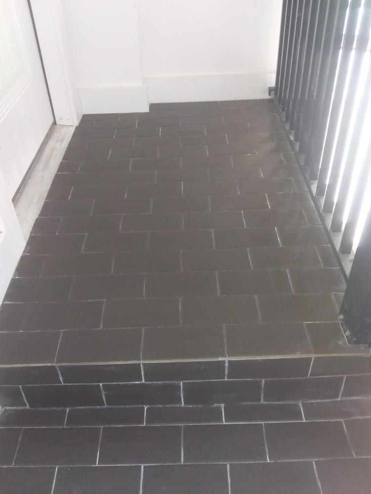 A black tiled floor in a room next to a radiator.