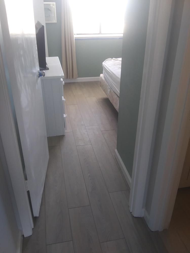 A hallway leads to a bedroom with a bed, dresser, and television.