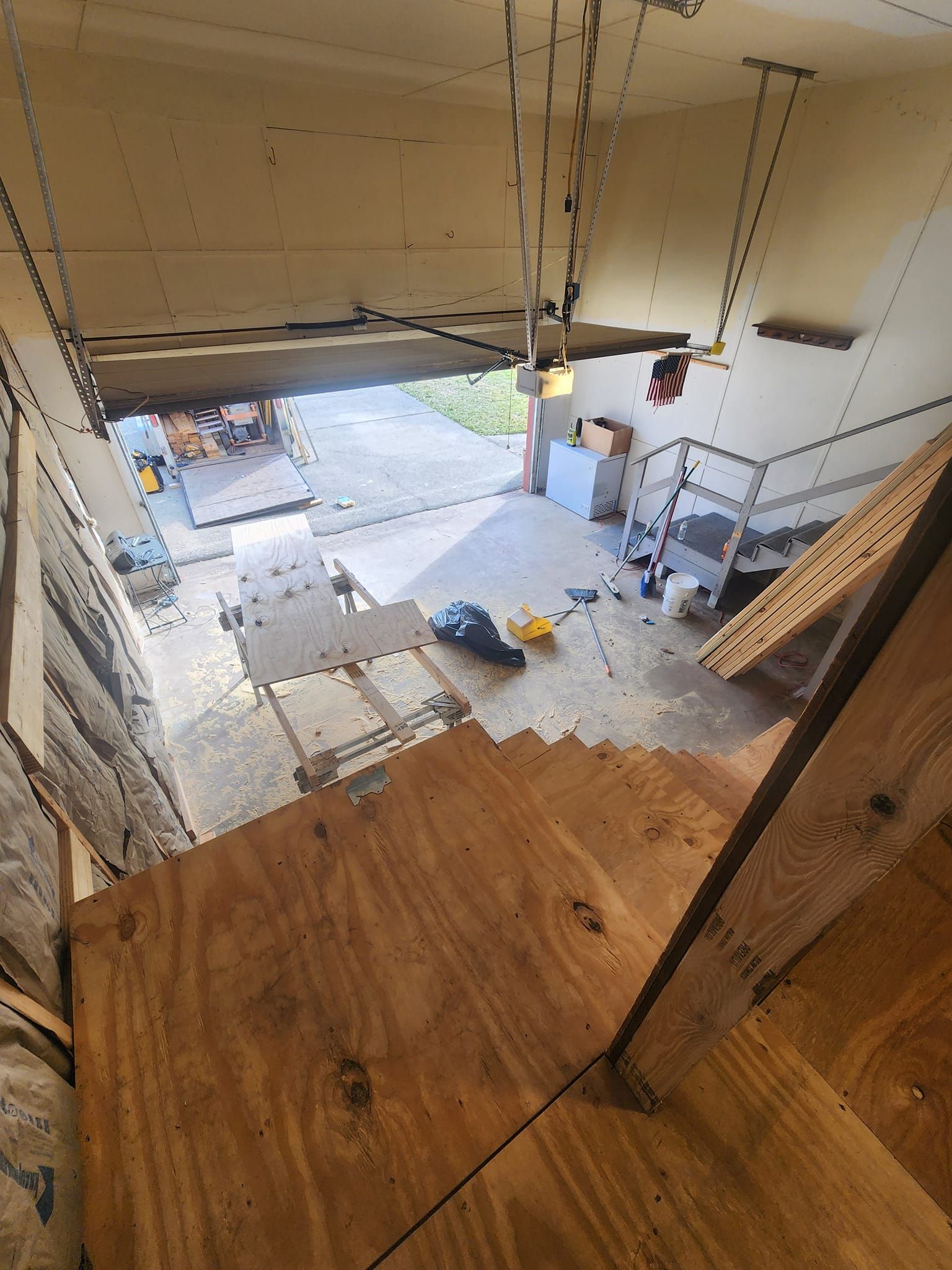 A wooden staircase leads up to a garage with a chain hanging from the ceiling.