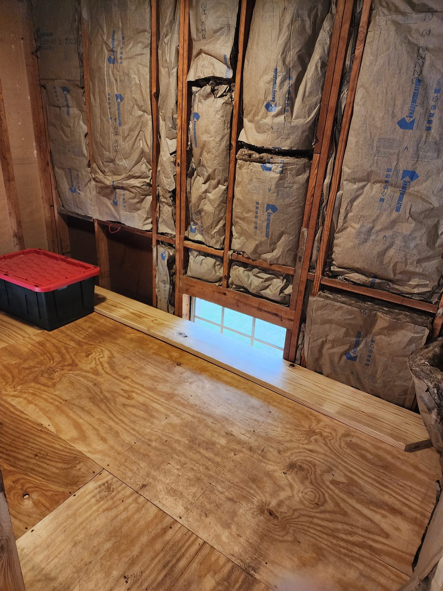 A room with a window and a wooden floor.