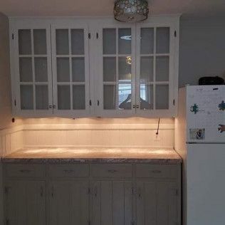 A kitchen with white cabinets and a white refrigerator.