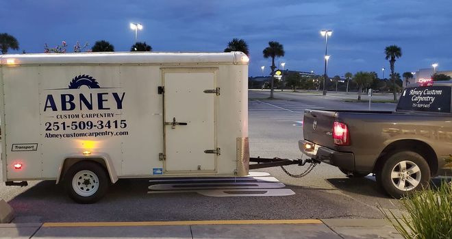 A truck is pulling a trailer that says abney on it.