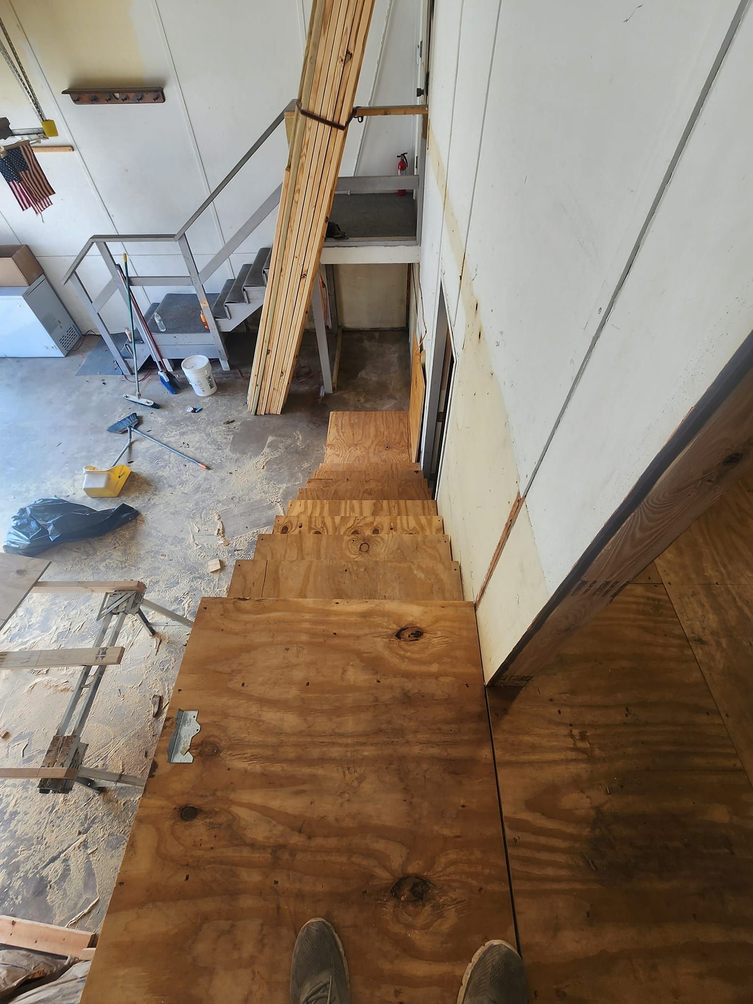 A person is standing on a wooden floor next to a staircase.