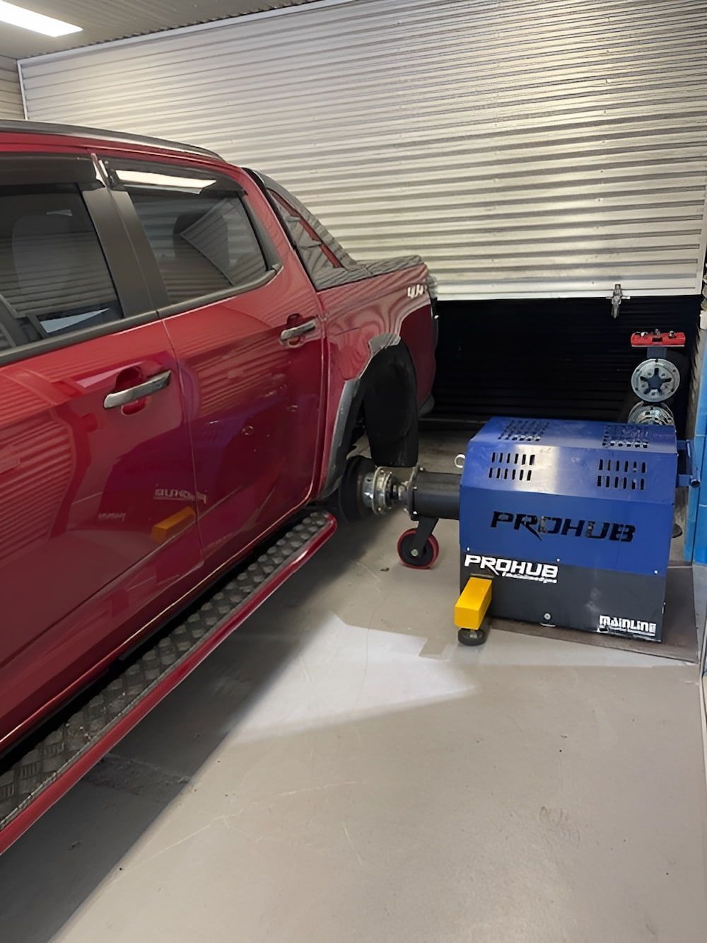 A Red Truck Is Parked In A Garage Next To A Machine — Hunter Automotive In Bungalow, QLD