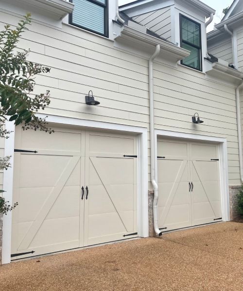 A row of white garage doors on a white house