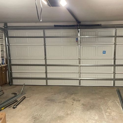 A large white garage door is open in a garage.