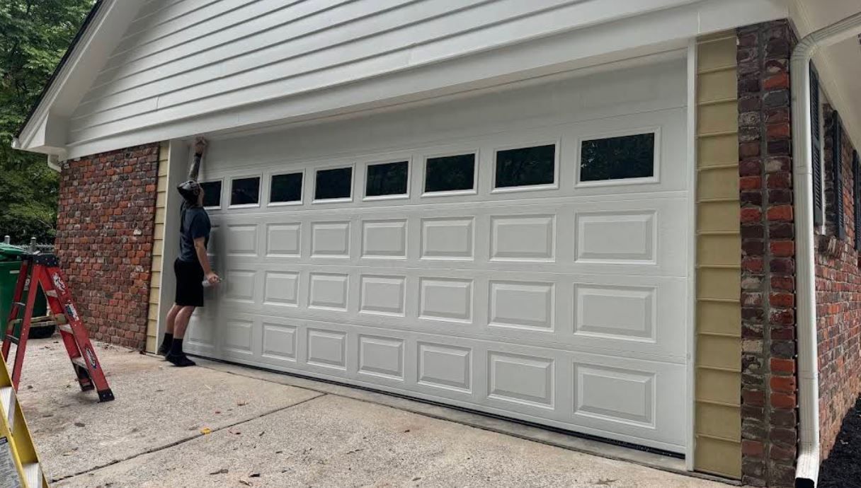 A man is standing in front of a white garage door.
