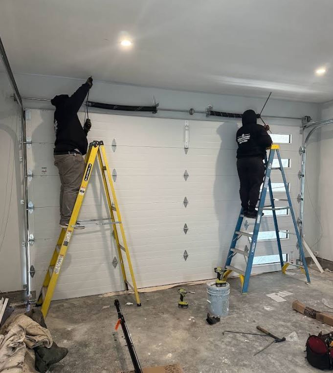 Two men are working on a garage door in a garage.