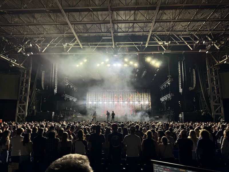 Concert stage with performers, bright lights, and a crowd of people.