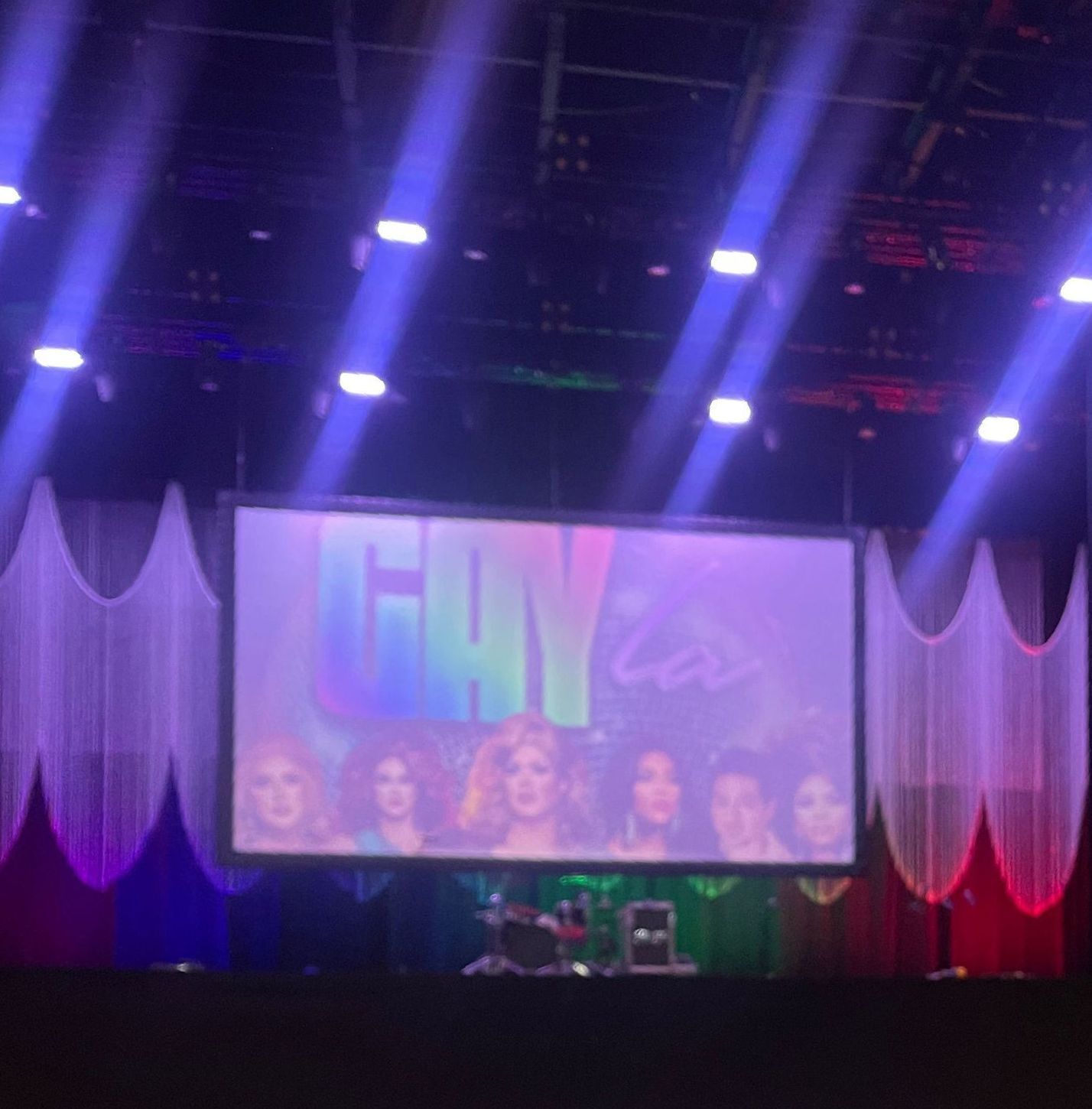 Stage lit with rainbow colors. Screen shows 
