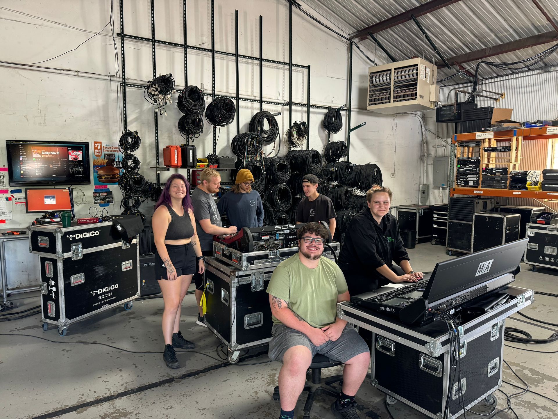 Group of people in a warehouse setting, likely setting up equipment for a show.