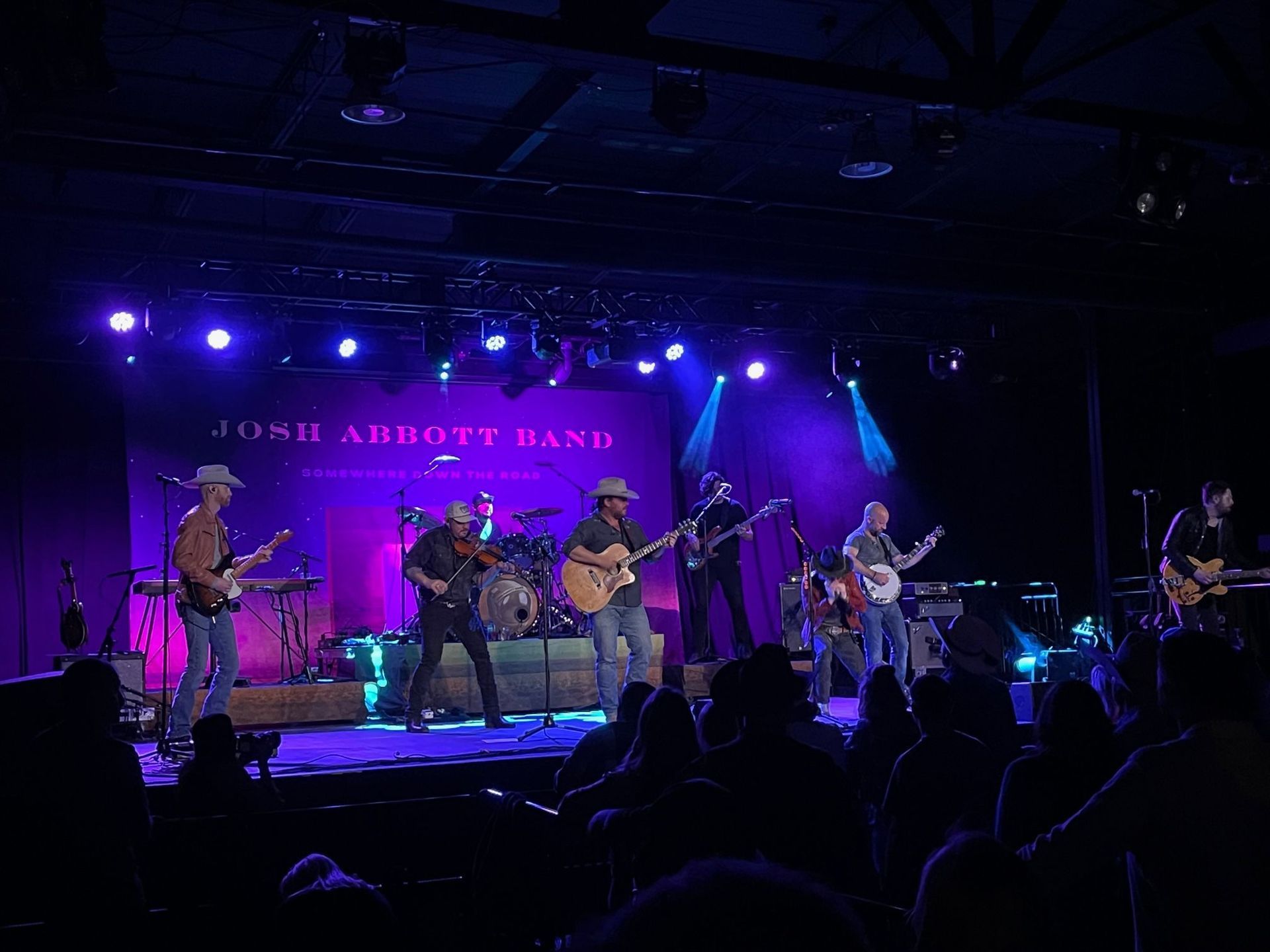 John Abbott Band performing on stage, lit with purple lights, in front of an audience.