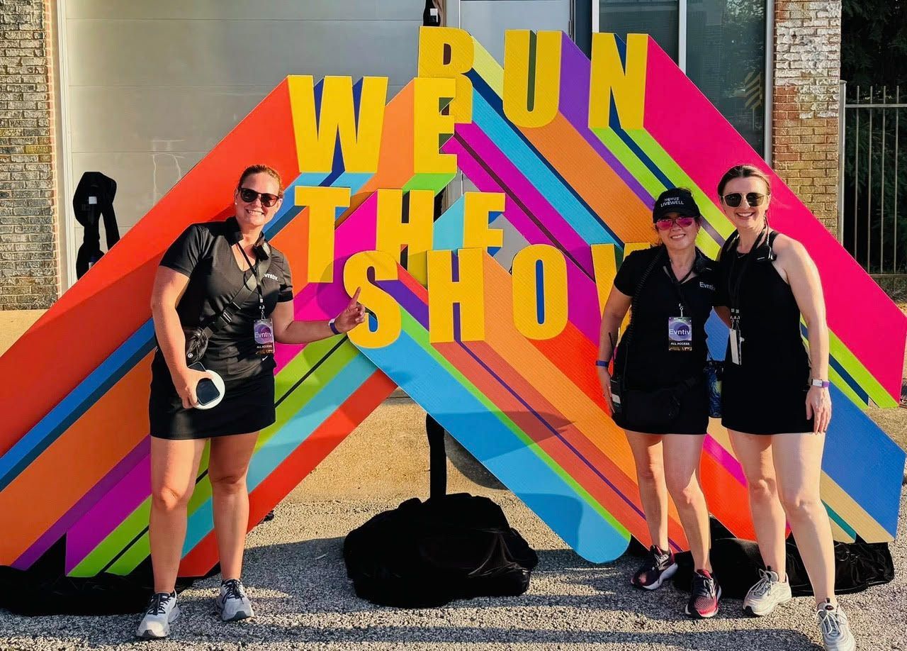 Event hall with large screens displaying a cityscape, round tables set for a meal, and decorative lighting.