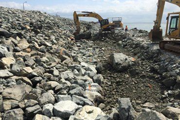 Two Yellow Excavators Working on a Rocky Embankment Near Water — CJD Investments (NQ) Pty Ltd in Mackay Harbour, QLD