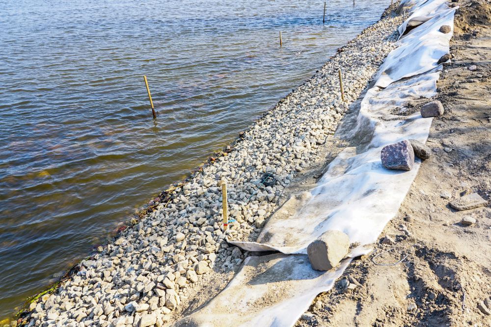 A chain link fence is surrounded by rocks and gravel in a grassy area.