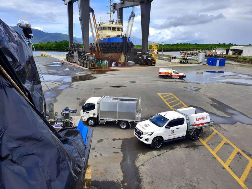 Two Trucks Are Parked In A Parking Lot In Front Of A Large Ship — Great Energy in Portsmith, QLD