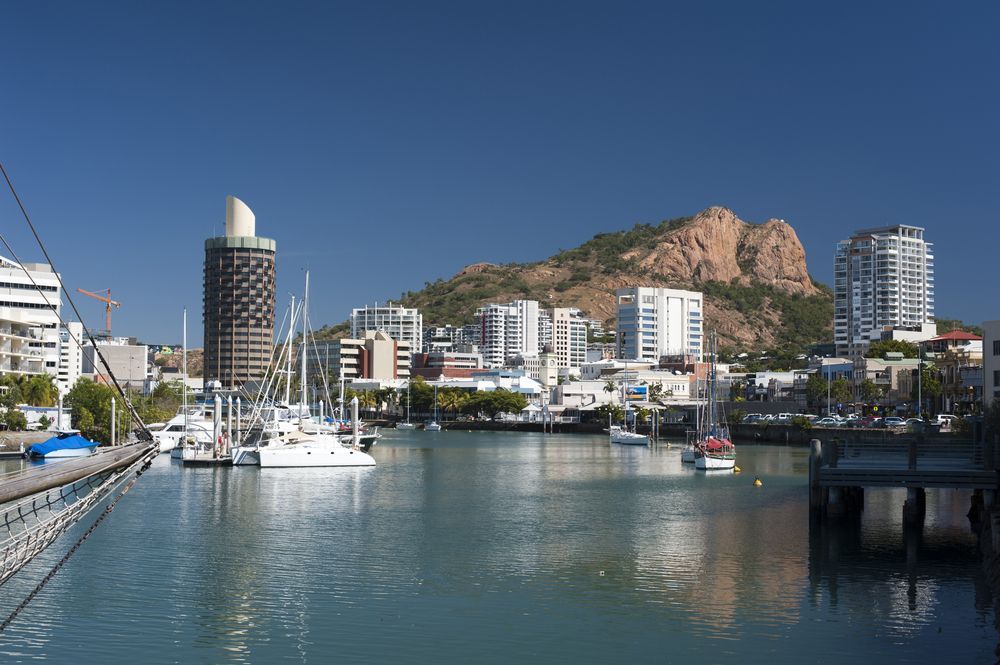 A Harbor With Boats And Buildings In The Background And A Mountain — Great Energy in Townsville, QLD
