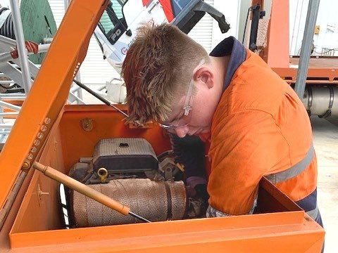 A Man In An Orange Vest Is Working On A Machine — Great Energy in Portsmith, QLD