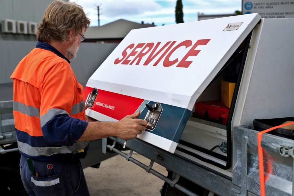 A Man Is Working On A Service Box On The Back Of A Truck — Great Energy in Portsmith, QLD