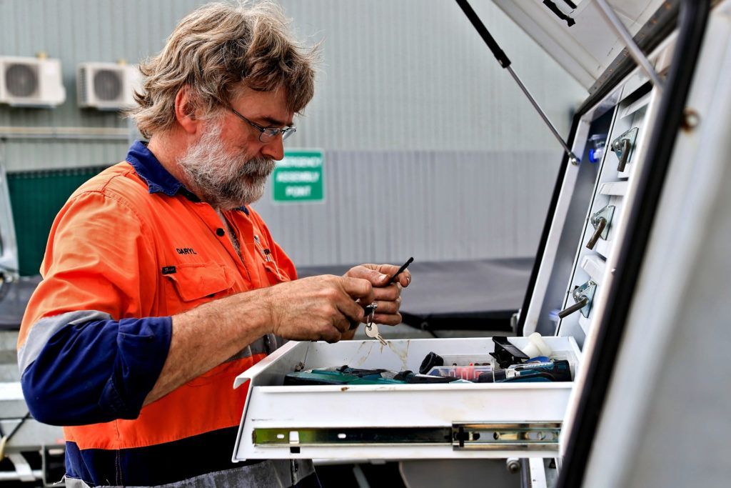 A Man In An Orange Shirt Is Working On A Machine — Great Energy in Perth, QLD