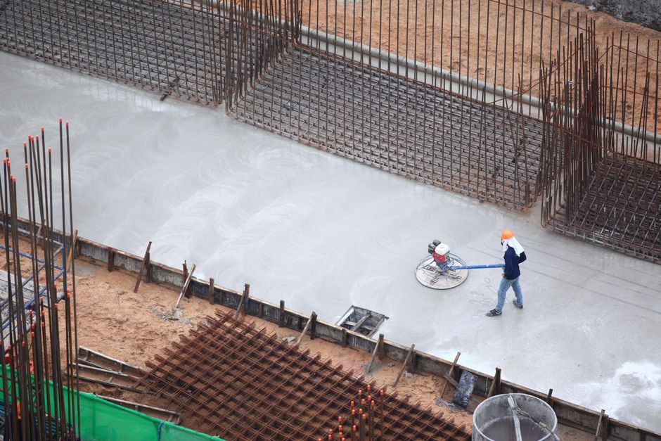 construction worker flattening the concrete floor